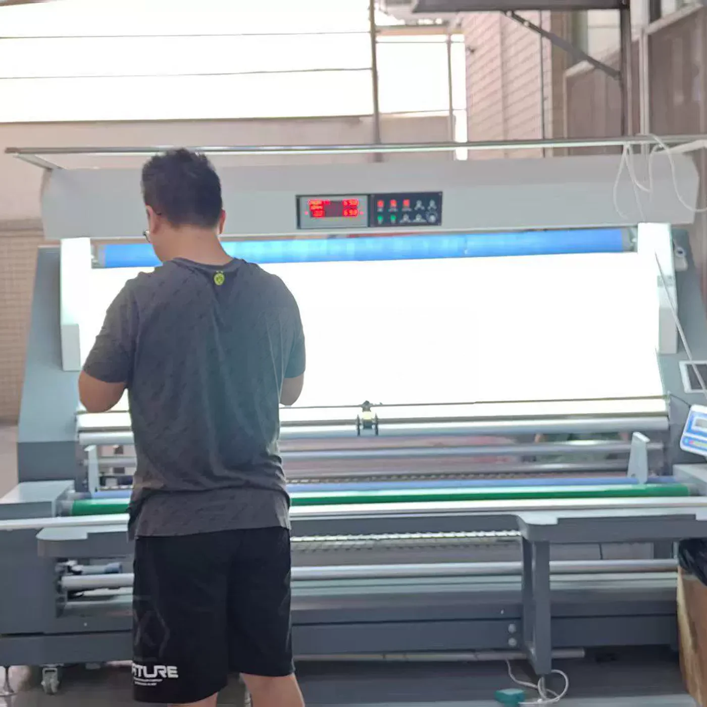 Operaria inspeccionando tejido en una máquina de revisión