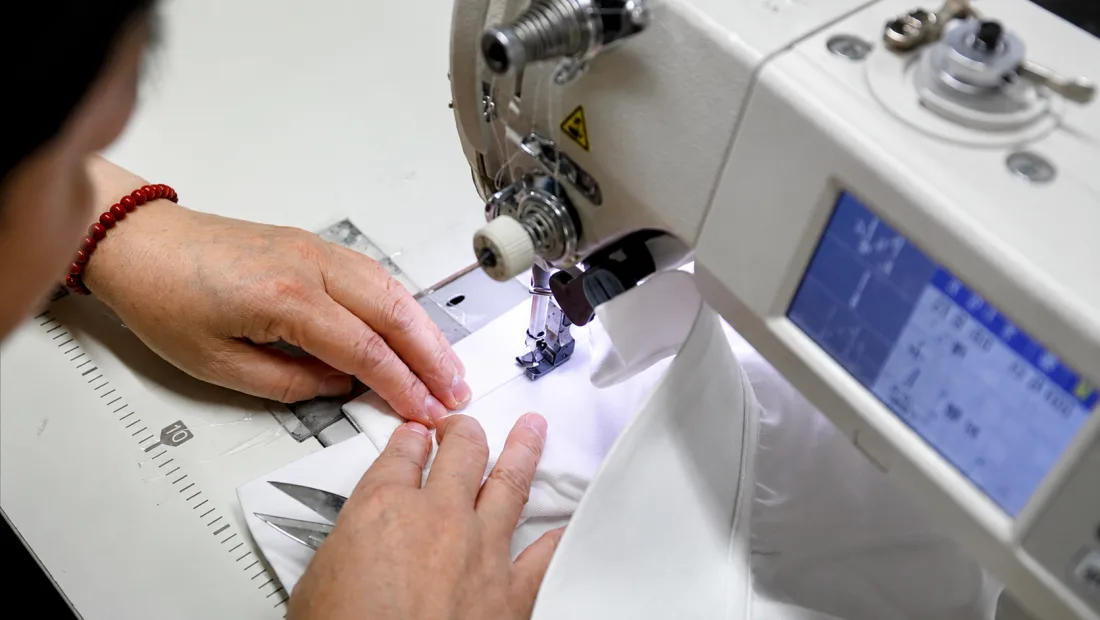 Close-up of jacket fabric being sewn on an industrial sewing machine